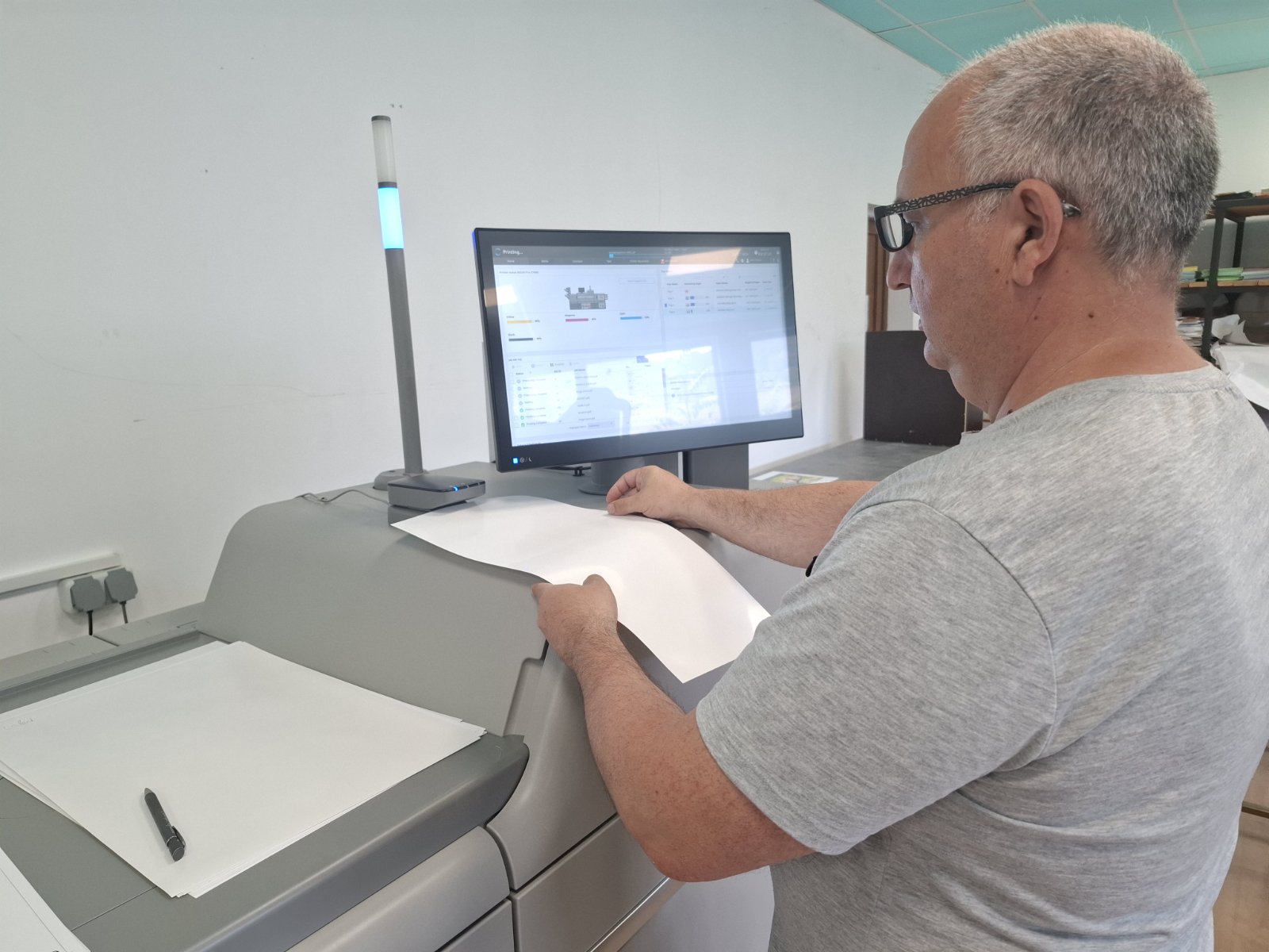 Оператор разглежда отпечатък до пресата Ricoh Pro C7500